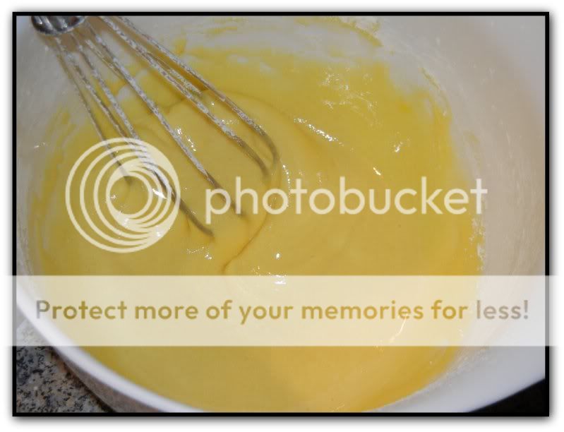 Whisking together the egg yolks and sugar in a white bowl with a metal whisk 